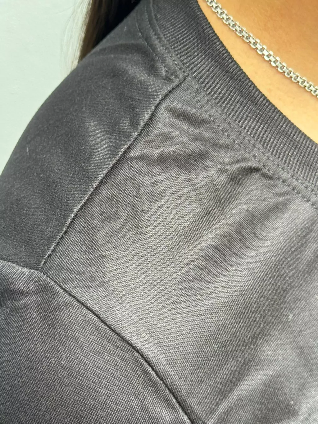 Baby look preta 100% poliéster – detalhe do decote e acabamento superior